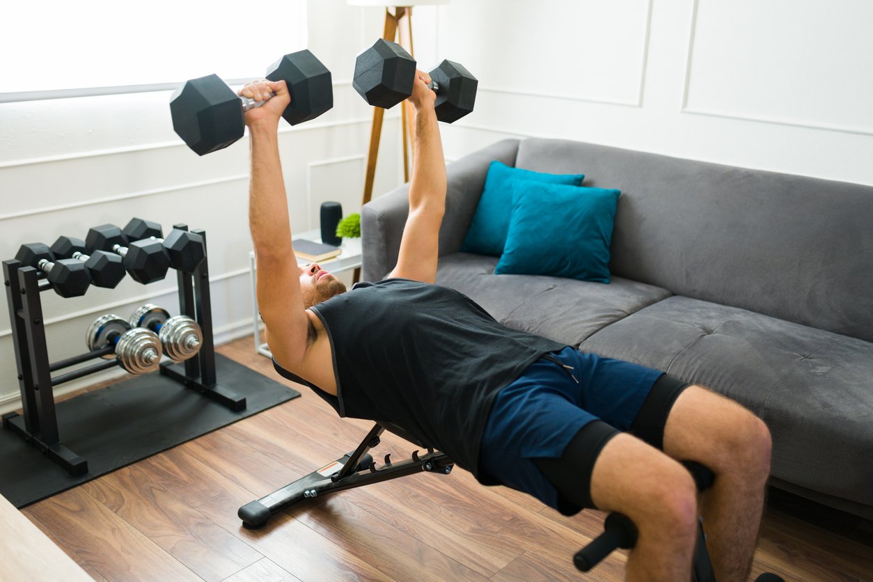 Mann beim Krafttraining mit Hantelbank zuhause