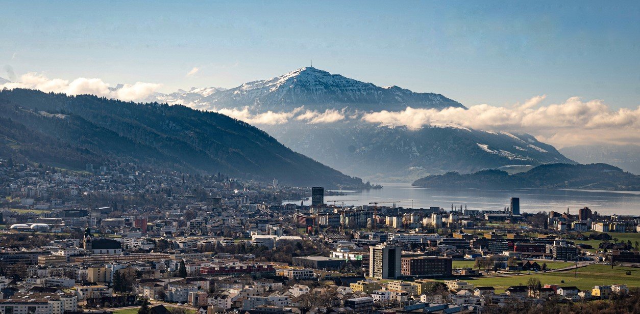 Bild der Stadt Zug: verschiedene Gebäude mit Blick auf See und Berge
